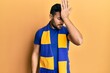 © Krakenimages.com - Young hispanic man football hooligan cheering game surprised with hand on head for mistake, remember error. forgot, bad memory concept.