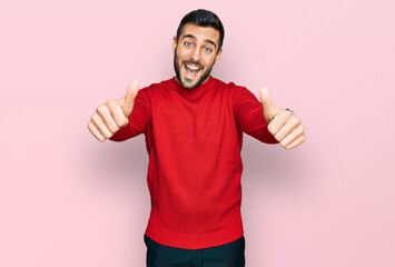 Young hispanic man wearing casual clothes approving doing positive gesture with hand, thumbs up smiling and happy for success. winner gesture.