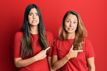 Poster - Hispanic family of mother and daughter wearing casual clothes over red background pointing aside worried and nervous with forefinger, concerned and surprised expression