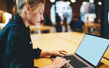 Wall Mural - Caucaisan woman browsing website via blank laptop computer with copy space area for internet advertising, skilled freelancer chatting and messaging via netbook with mock up screen for your website