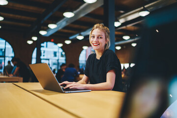 portrait of happy caucaisan copywriter smiling at camera while doing distance job in coworking space