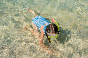 Wall Mural - Close up of toddler girl learning snorkeling on shallows. Child immersing the head in water. Kids diving with snorkel mask and tube on the water s edge. Family vacation concept