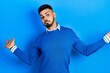 © Krakenimages.com - Young hispanic man with beard wearing casual blue sweater clueless and confused expression with arms and hands raised. doubt concept.