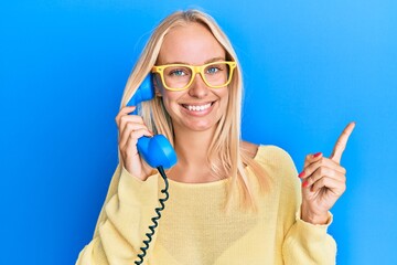 Poster - Young blonde girl holding vintage telephone smiling happy pointing with hand and finger to the side