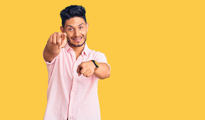 Handsome latin american young man wearing casual summer shirt pointing to you and the camera with fingers, smiling positive and cheerful