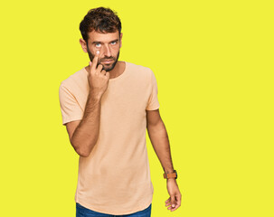 Poster - Handsome young man with beard wearing casual tshirt pointing to the eye watching you gesture, suspicious expression