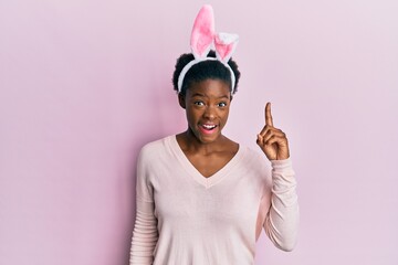 Canvas Print - Young african american girl wearing cute easter bunny ears pointing finger up with successful idea. exited and happy. number one.