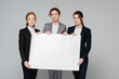 © LIGHTFIELD STUDIOS - Businesswomen with white placard looking at camera isolated on grey