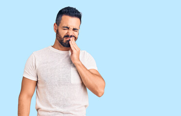 Canvas Print - Young hispanic man wearing casual clothes touching mouth with hand with painful expression because of toothache or dental illness on teeth. dentist