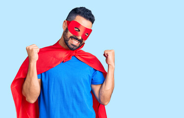 Poster - Young hispanic man wearing super hero costume very happy and excited doing winner gesture with arms raised, smiling and screaming for success. celebration concept.