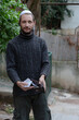 Man showing empty wallet. Jewish man wearing kippah in Hebrew or yarmulke with green trees in the background, beard wearing black sweatshirt. No money concept against the background of the pandemic