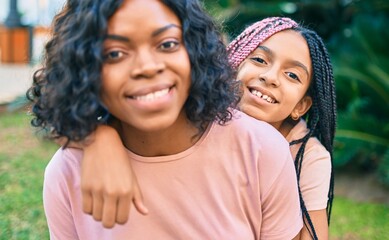 Sticker - Beautiful african american mother and daughter smiling happy and hugging. Standing with smile on face standing at the park.