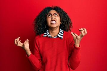 beautiful african american woman with afro hair wearing sweater and glasses crazy and mad shouting a