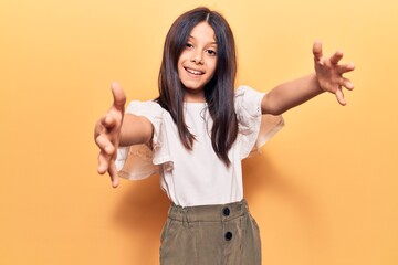 Sticker - Beautiful child girl wearing casual clothes looking at the camera smiling with open arms for hug. cheerful expression embracing happiness.