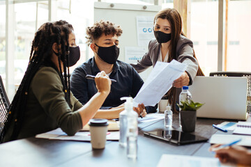 Business team wearing protective masks while meeting in the office during the COVID-19 epidemic