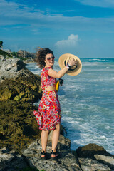 Wall Mural - beautiful girl in a hat and a black dress looks at the ocean. TULUM, Mexico