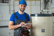 © Grustock - Technician servicing an hot-water heater. Man check equipment of the boiler-house - thermometer.
