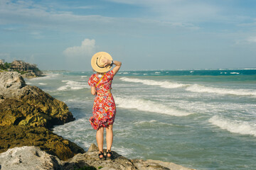 Wall Mural - beautiful girl in a hat and a black dress looks at the ocean. TULUM, Mexico