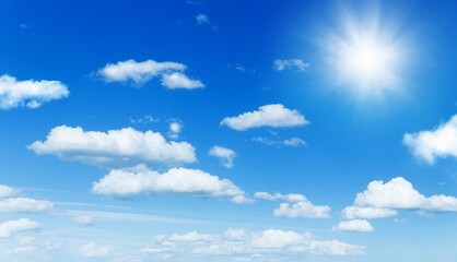 Wall Mural - sunny background, blue sky with white clouds and sun as summer or spring natural background.