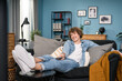 © ABCreative - Surfing the channels. Cheerful young European Caucasian teenager male holding remote control watching comedy on TV laughing with humorous jokes while sitting on the couch at living room at home