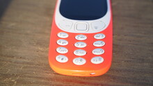 Old Generation Keypad, Phone Isolated On Wooden Table Background. Old 2g Mobile Cell Phone With Small Number Keys. Nokia Branded Company In India.