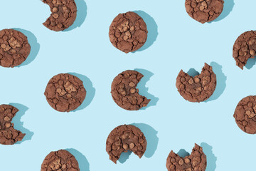 Creative pattern made with chocolate chip cookies on pastel blue background. Happy sweet fun life idea. Sunny food or dessert concept. Spring or summer layout.