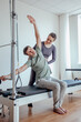 © Виктория Карлова - Reformer Pilates.An attractive man working out with a pilates instructor in the gym