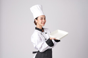 Beautiful young asian woman chef holding empty white plate on white background.