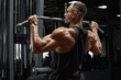 Muscular man workout in gym, doing exercise for back, lat pulldown. Strong male rear view