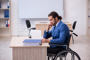 Young male employee in wheel-chair working in the office