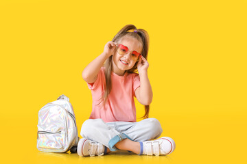 Cute little schoolgirl on color background