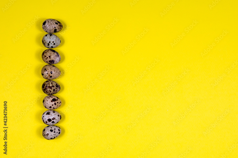 Quail eggs lie in a row on a yellow background. Healthy eating. View from above. Place for an inscription. - obrazy, fototapety, plakaty 