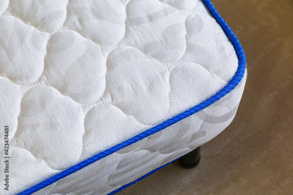 Modern orthopedic mattress on bed in room, closeup