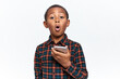 Portrait of adorable funny little dark skinned boy in plaid shirt opening mouth in astonishment watching video online, browsing social networks on smart phone. Parental control and adult content