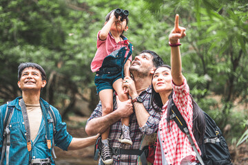 A group of young Asians are planning and looking at maps for camping in the forest.Asian and caucasian are backpackers.Tourism, adventure and summer vacation concept