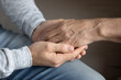 © fizkes - Crop close up of adult grownup son hold elderly father hand show love and care in family relations. Attentive millennial man kid child support comfort unhappy sad mature dad. Bonding, unity concept.