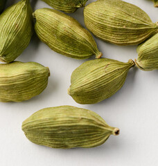 Square photo of green whole dried cardamom seeds isolated on a white background