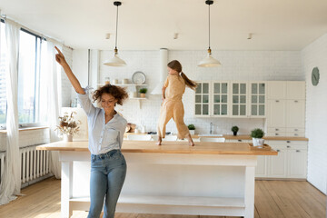overjoyed young caucasian mother and little 8s daughter have fun dancing together in new renovated k