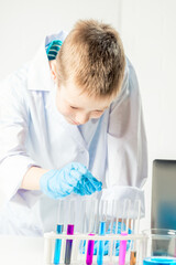 Wall Mural - a schoolboy studies multi-colored substances in test tubes, conducts experiments - a portrait on a w