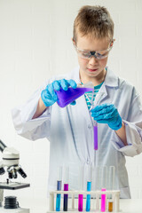 Wall Mural - a schoolboy with a microscope examines chemicals in test tubes, conducts experiments - a portrait on