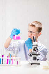 Wall Mural - a schoolboy with a microscope examines chemicals in test tubes, conducts experiments - a portrait on