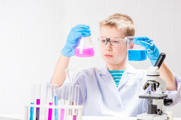 Wall Mural - a schoolboy with a microscope examines chemicals in test tubes, conducts experiments - a portrait on