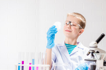 Wall Mural - a schoolboy with a microscope examines chemicals in test tubes, conducts experiments - a portrait on