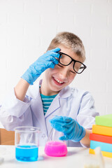 Wall Mural - a schoolboy studies multi-colored substances in test tubes, conducts experiments - a portrait on a w