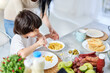 © Friends Stock - Love to cook. Curious little hispanic boy helping his mom preparing a meal for lunch, standing in the kitchen at home together