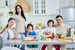 © Friends Stock - Eating together. Smiling hispanic parents spending time with their little children, having breakfast together at home