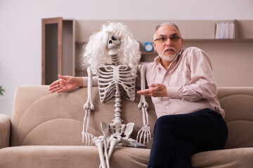 Old man sitting on the sofa with the female skeleton