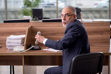 Old male employee sitting in the office