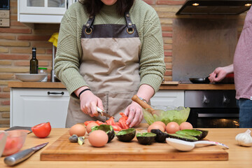 Wall Mural - Unrecognizable woman cutting tomatoes. Cooking mediterranean and healthy food.