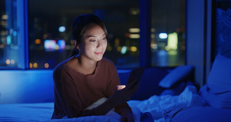 Poster - Woman check on smart phone and sit on bed in the even